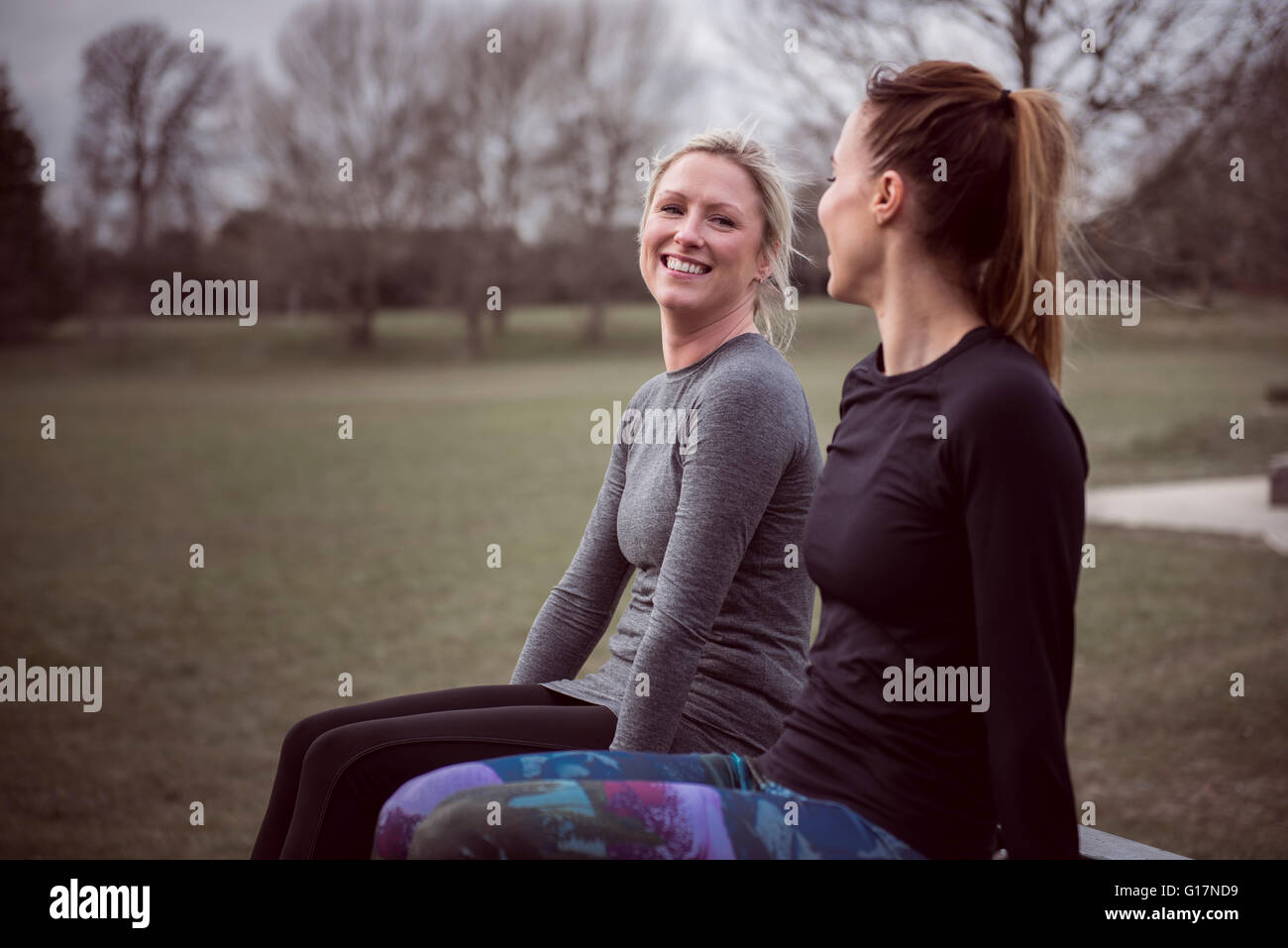 Les femmes portant des vêtements de sport dans la zone assis face à face smiling Banque D'Images