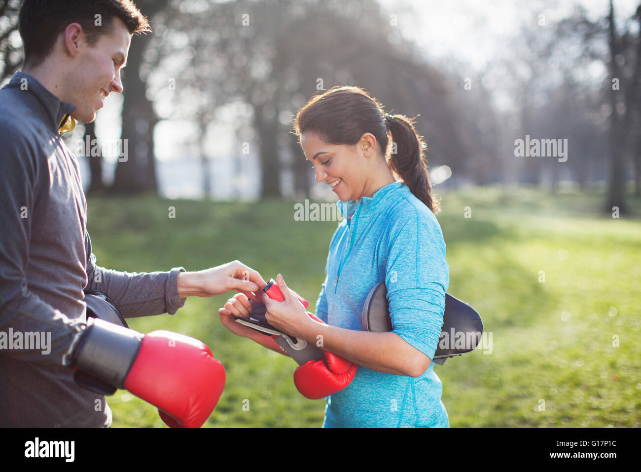 Young man and woman putting on gants de boxe pour la formation dans park Banque D'Images Young man and woman putting on gants de boxe pour la formation dans park Banque D'Images