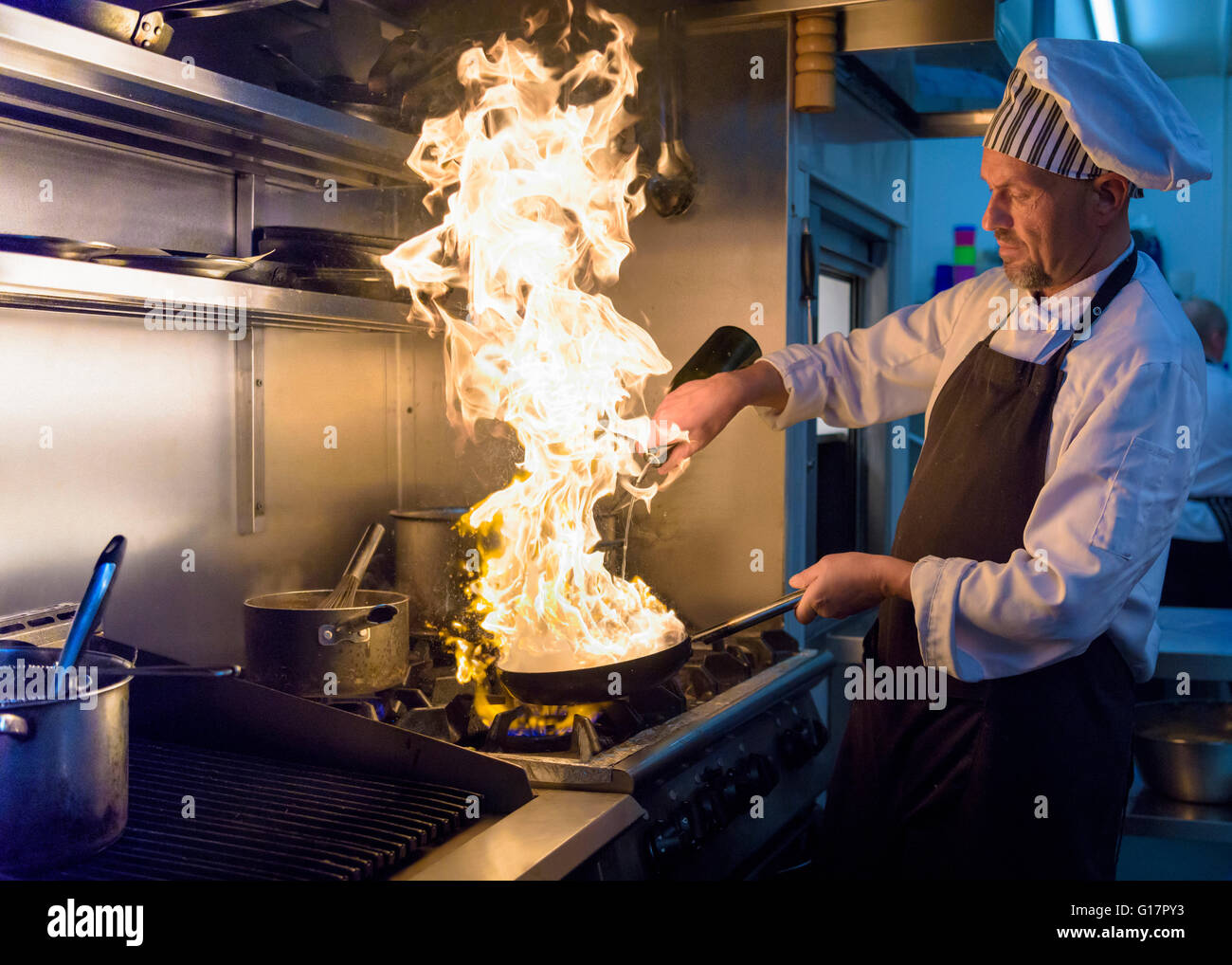 Chef avec pan de flammes dans la cuisine restaurant traditionnel italien Banque D'Images
