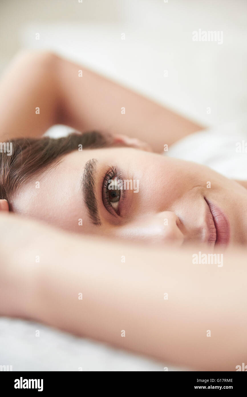 Close up portrait of beautiful young woman lying on bed Banque D'Images