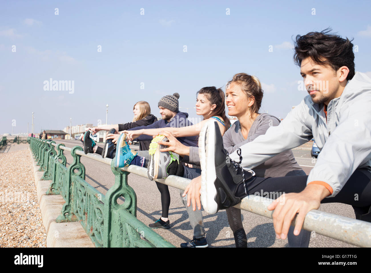 Cinq coureurs, garçons et filles, de préchauffage, de toucher les orteils à la plage de Brighton Banque D'Images