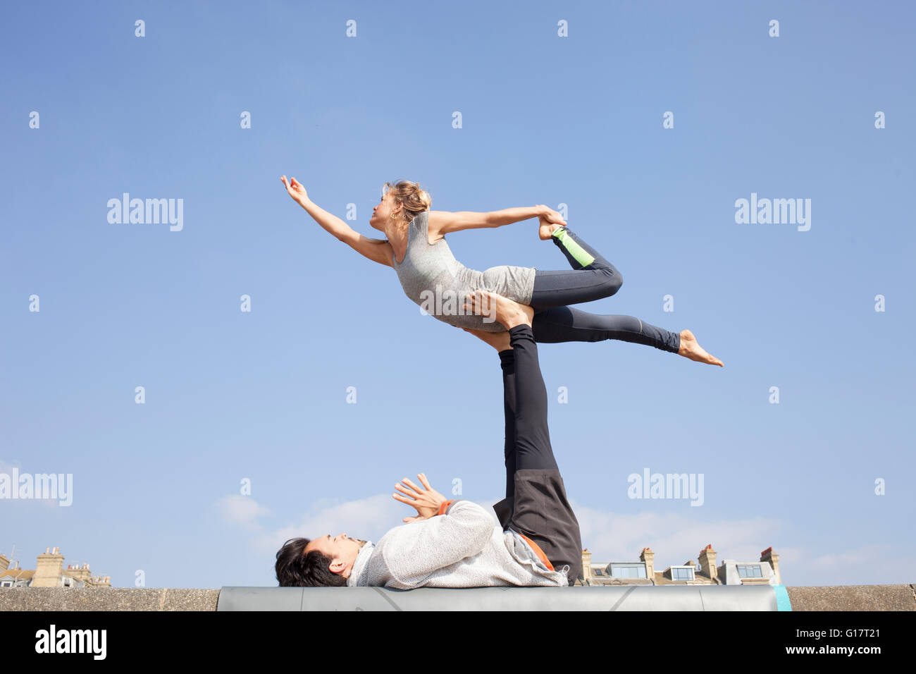 L'homme et la femme pratiquant le yoga acrobatique sur mur Banque D'Images