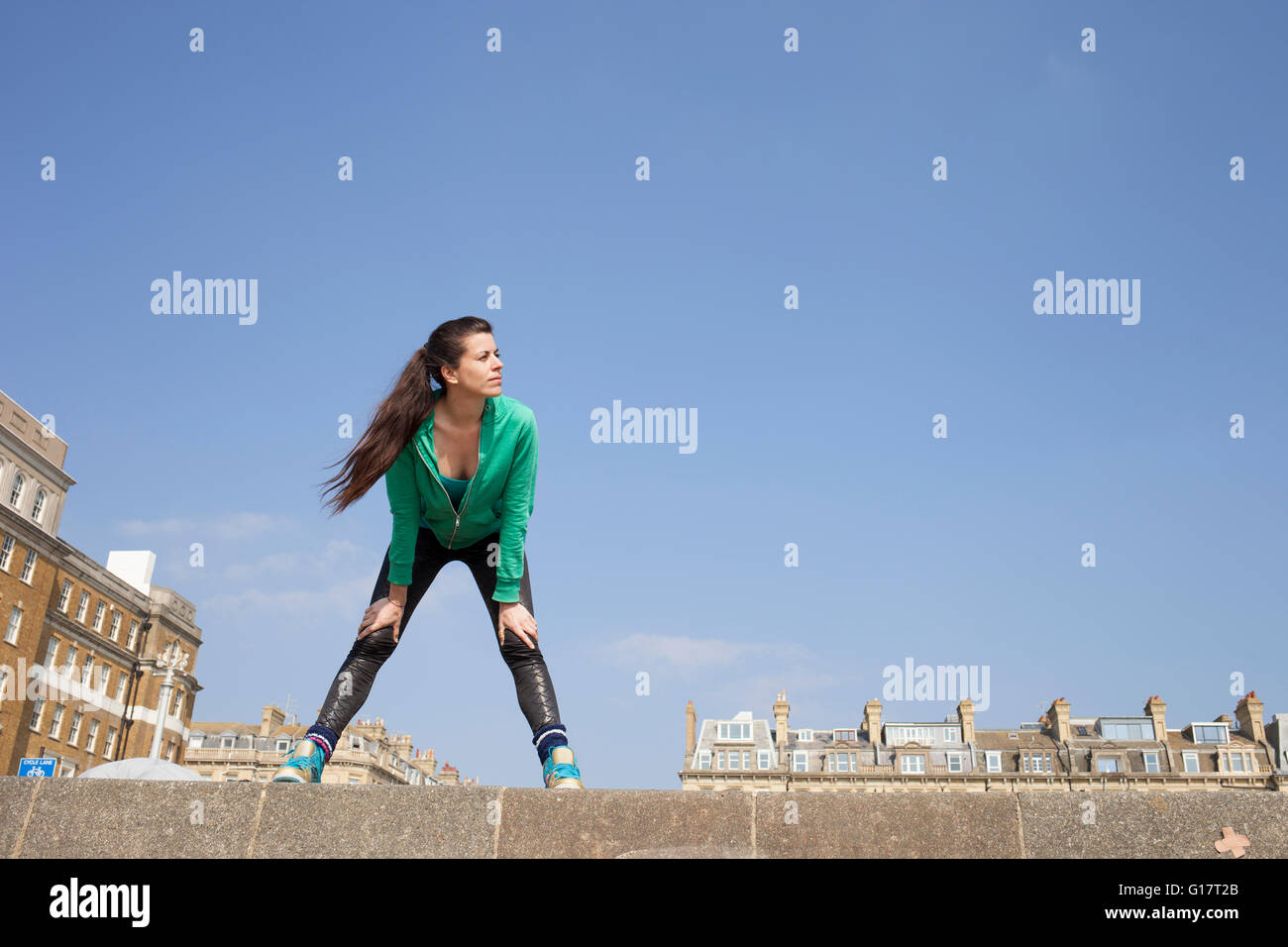 Épuisé female runner standing on wall prendre une pause Banque D'Images