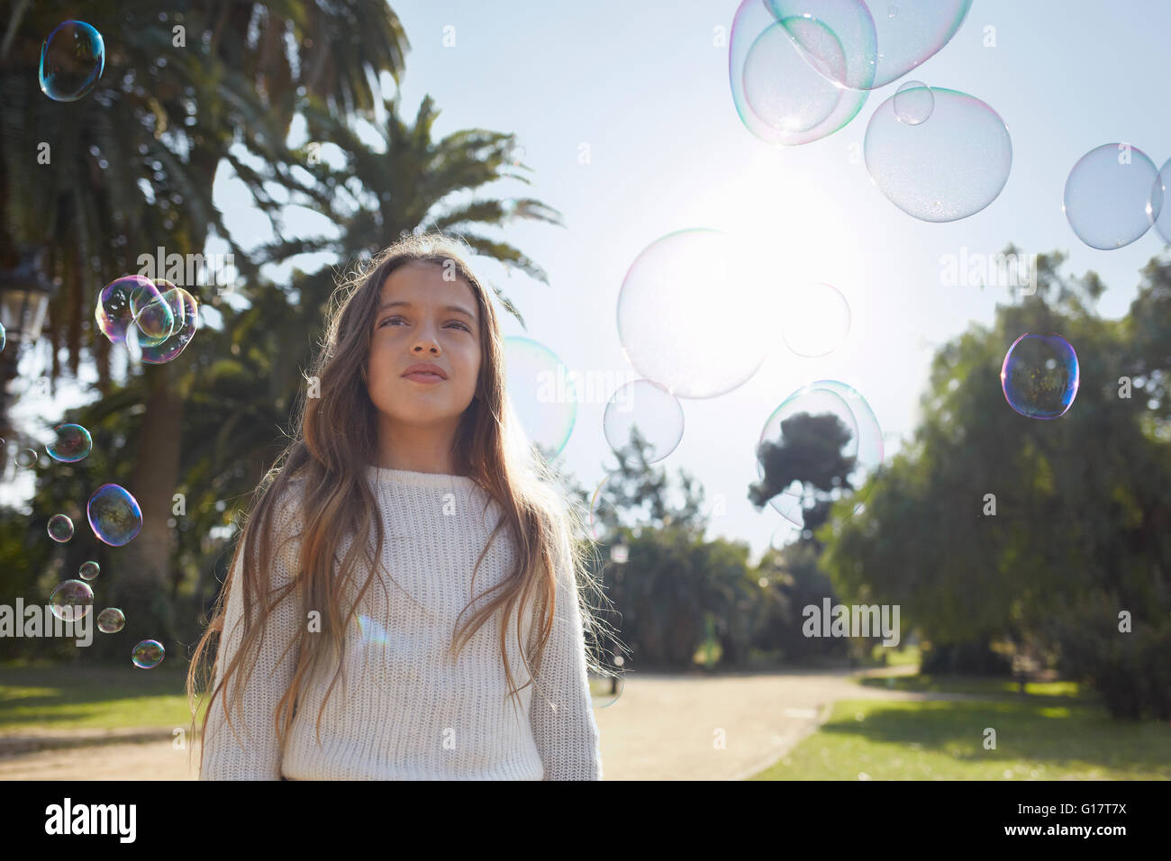 Jeune fille dans un parc entouré de bulles à la suite Banque D'Images