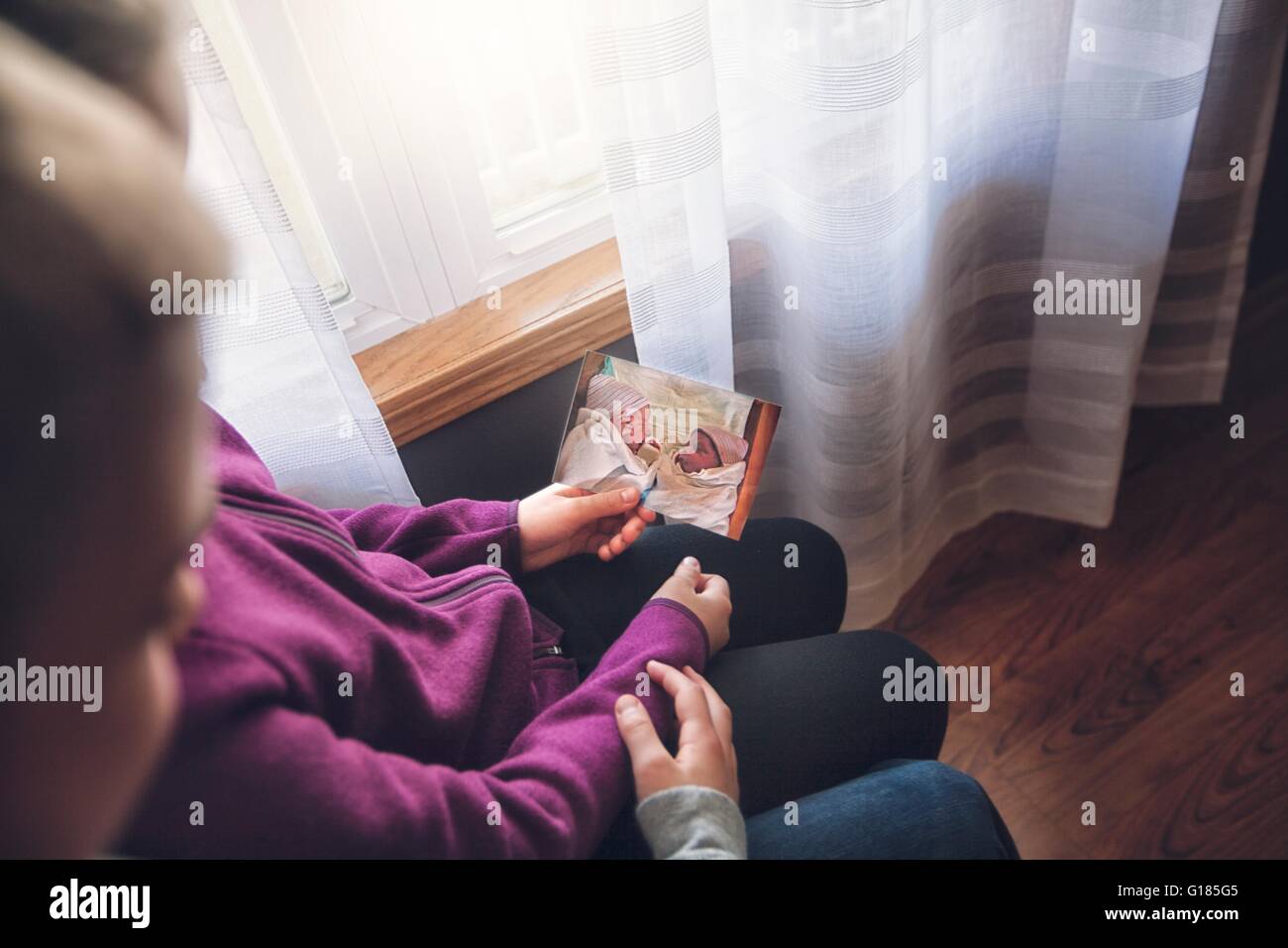 Plus d'épaule du garçon et fille twins holding photo d'eux que des bébés Banque D'Images