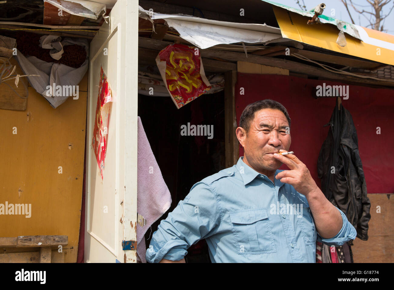 Chinese man smoking a cigarette en face de sa maison, dans un quartier pauvre à Nanjing, Chine Banque D'Images