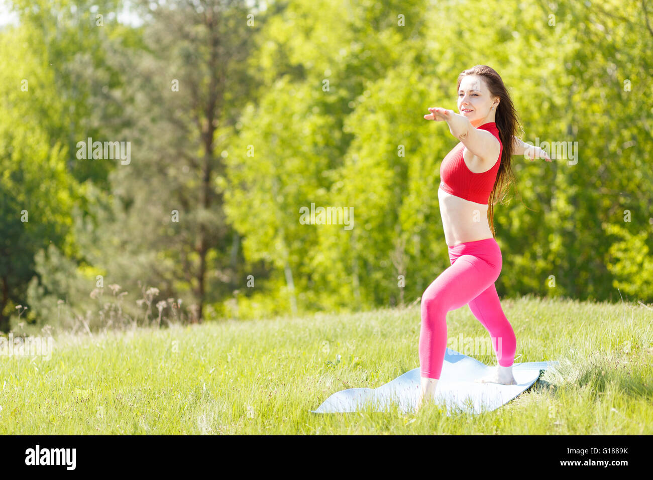 Les jeunes slim woman practicing yoga warrior pose. Athletic Girl doing yoga à l'extérieur Banque D'Images