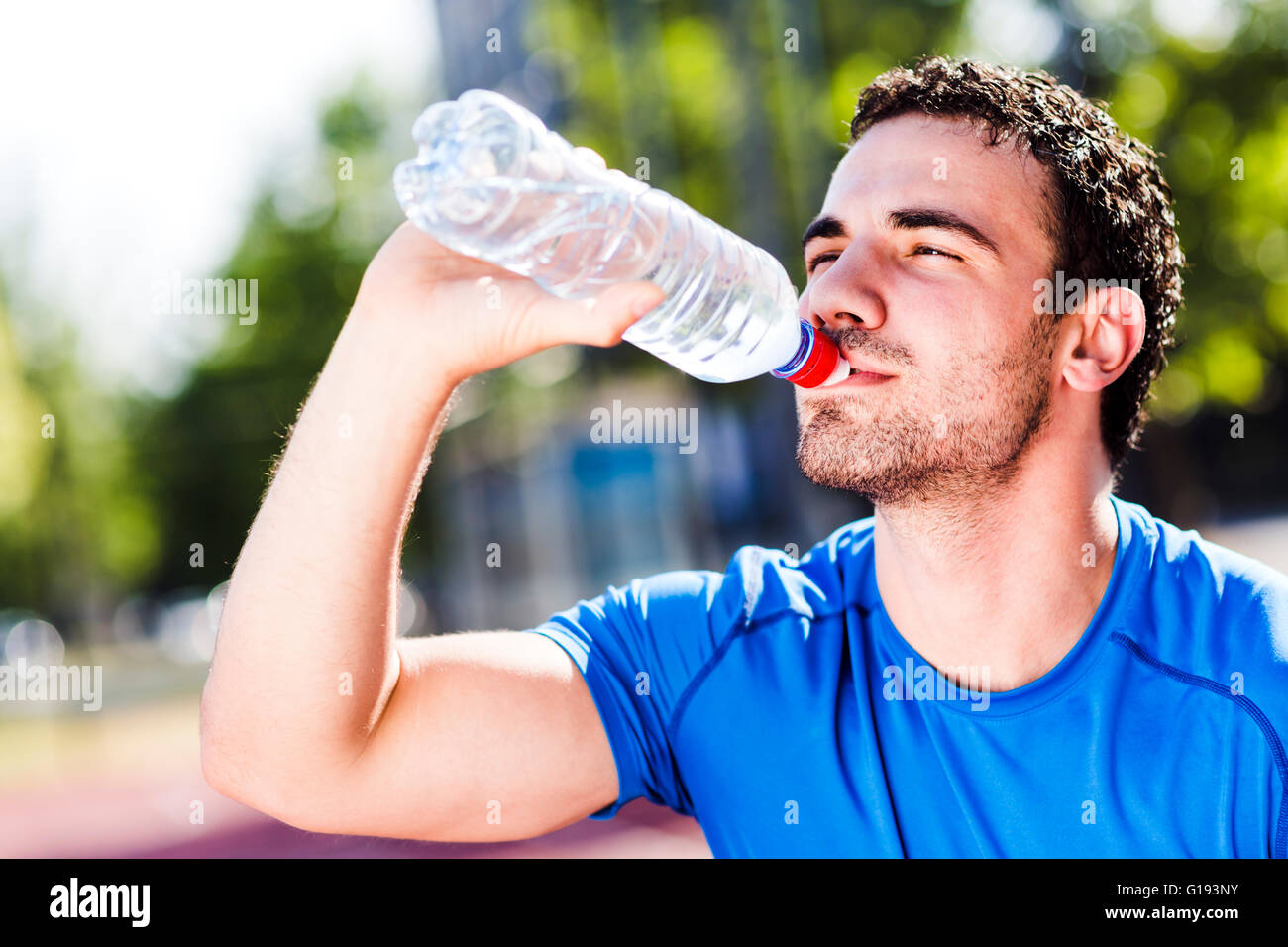 Beau jeune homme athlétique l'eau potable au cours d'une chaude journée d'été pour rafraîchir son corps et âme Banque D'Images