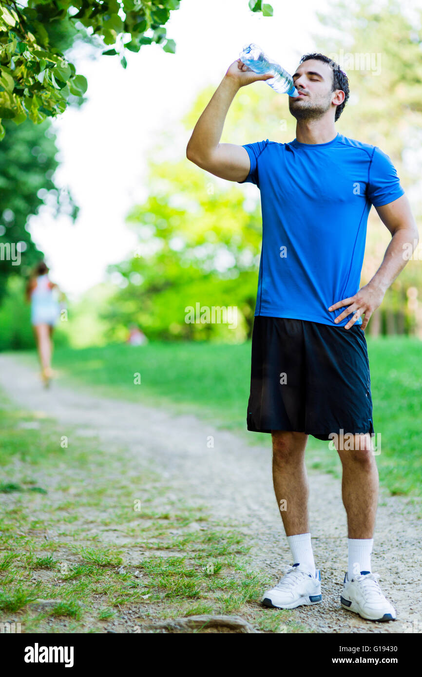Les jeunes de l'athlète masculin de l'eau potable dans le parc après le jogging Banque D'Images