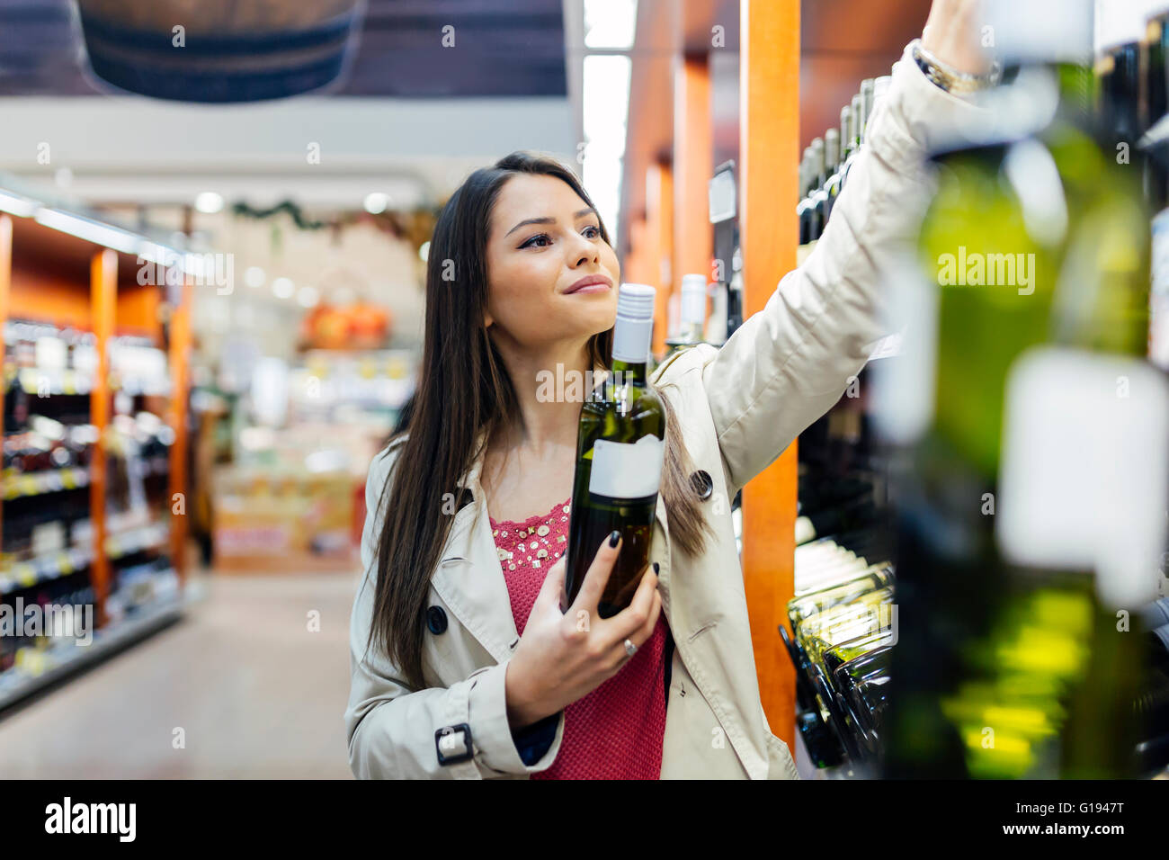 Femme de décider quel vin pour l'achat et shopping in supermarket Banque D'Images