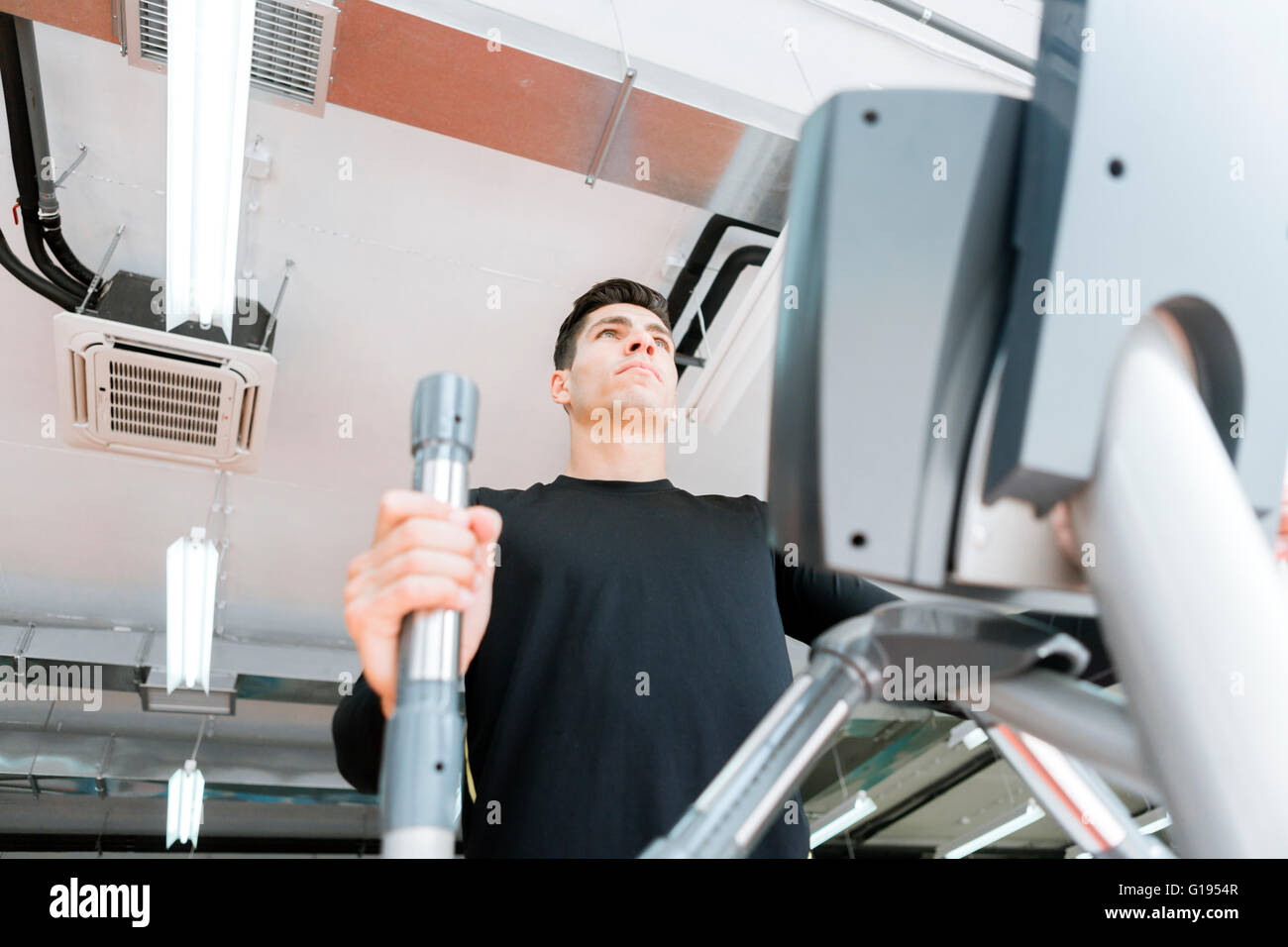 Jeune homme fit travailler sur un entraîneur elliptique dans une salle de sport Banque D'Images