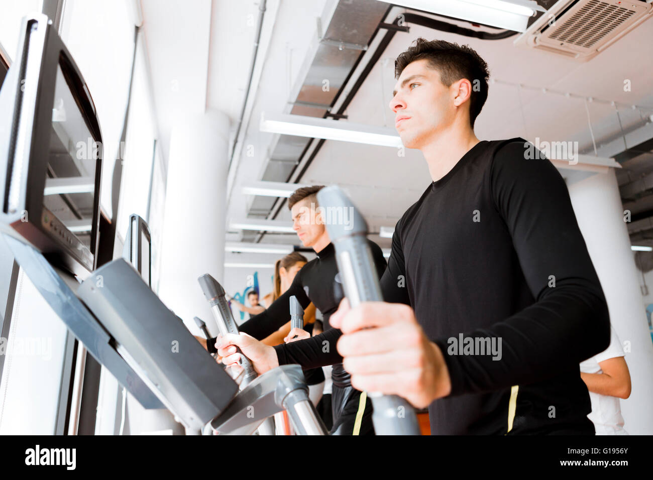 Jeune groupe de personnes en bonne santé qui travaillent dehors sur un entraîneur elliptique dans un centre de remise en forme Banque D'Images