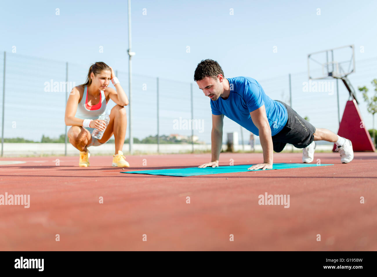 Jeune, belle, en forme et en bonne santé l'entraîneur personnel comptant push-ups et motivant Banque D'Images