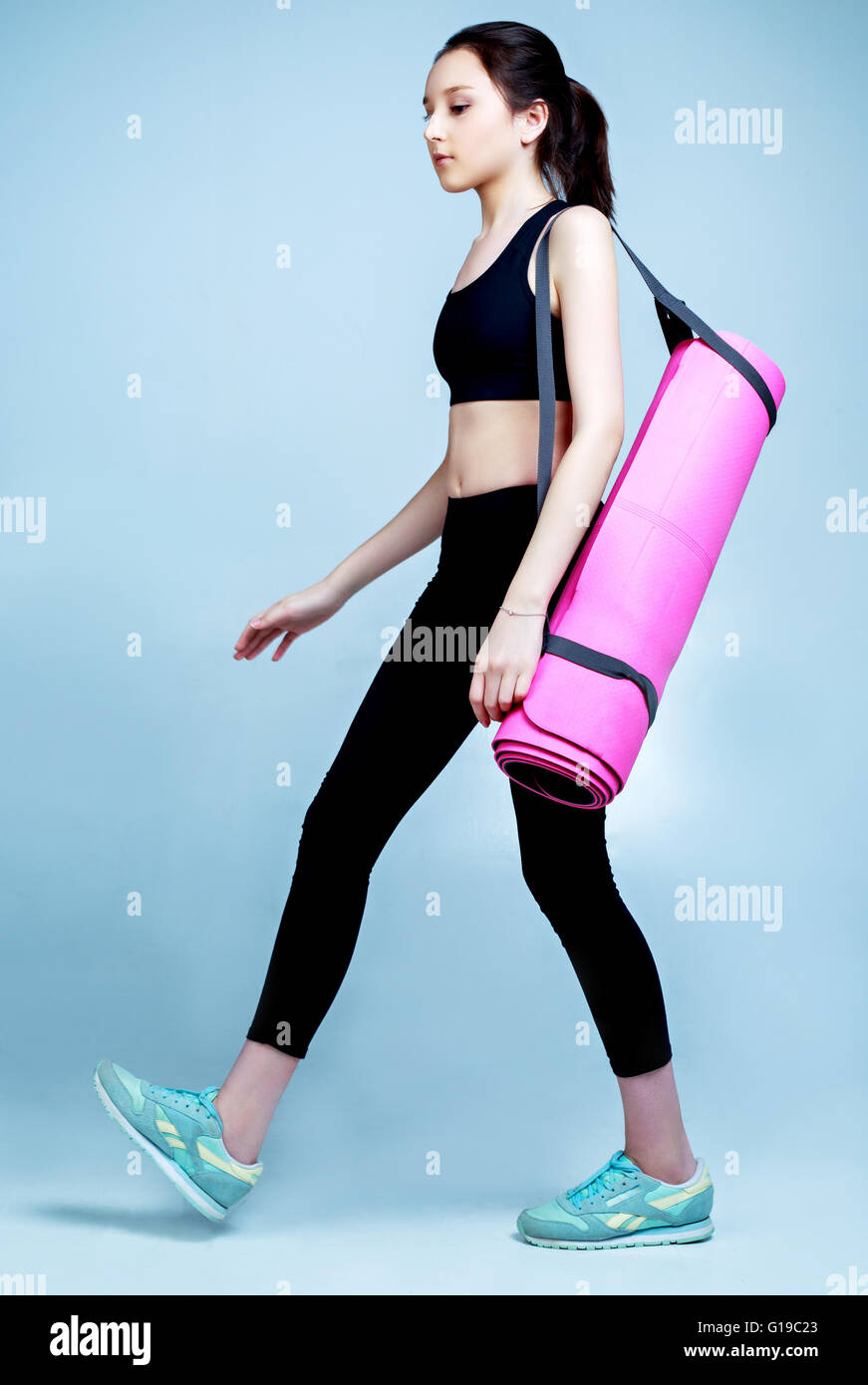 Teenage girl wearing vêtements de sport avec un tapis de yoga Banque D'Images