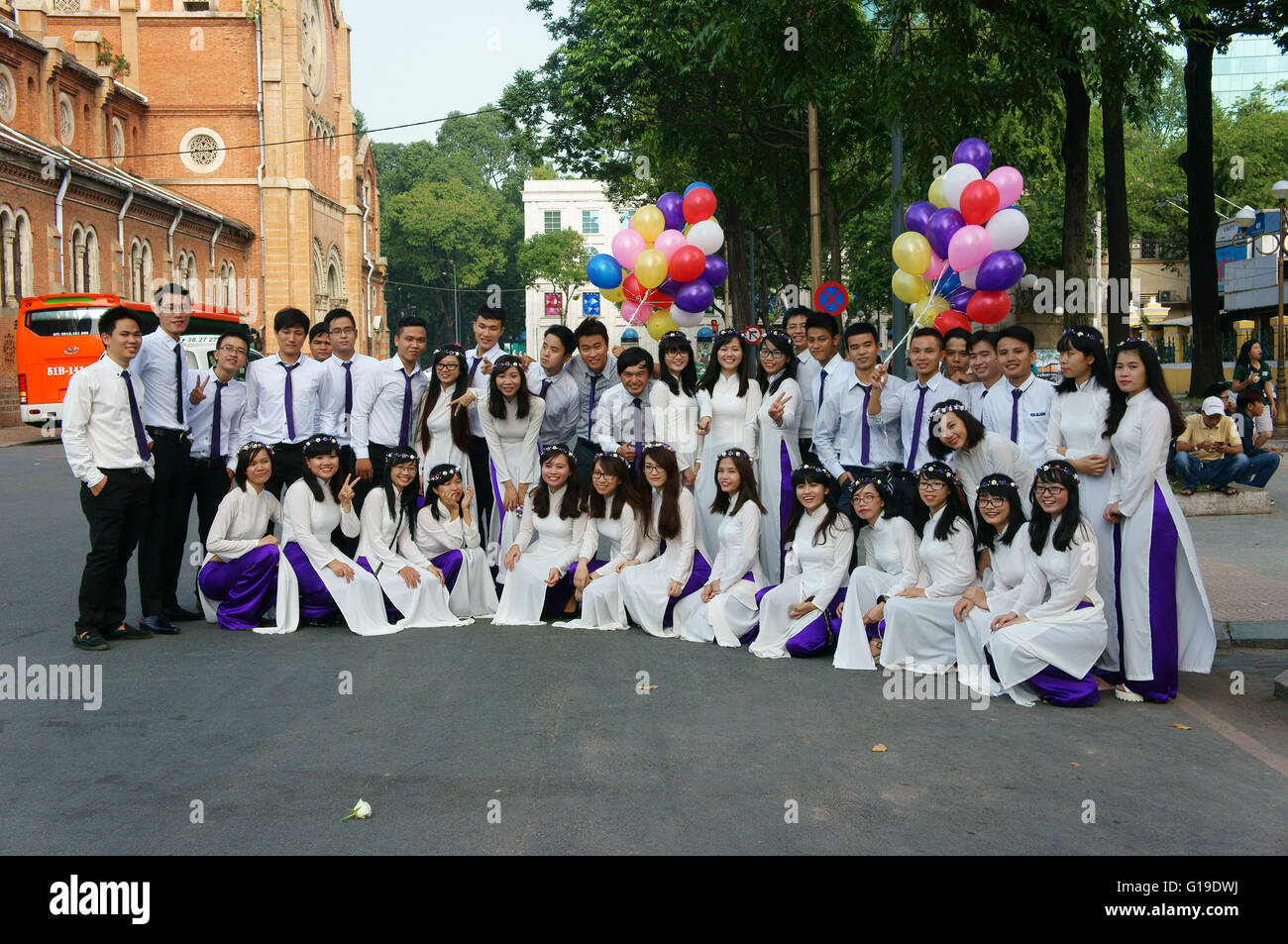 HO CHI MINH ville, VIET NAM, foule d'étudiants vietnamiens en vêtements traditionnels, ao dai, le tir à la Cathédrale Notre Dame, au Vietnam Banque D'Images