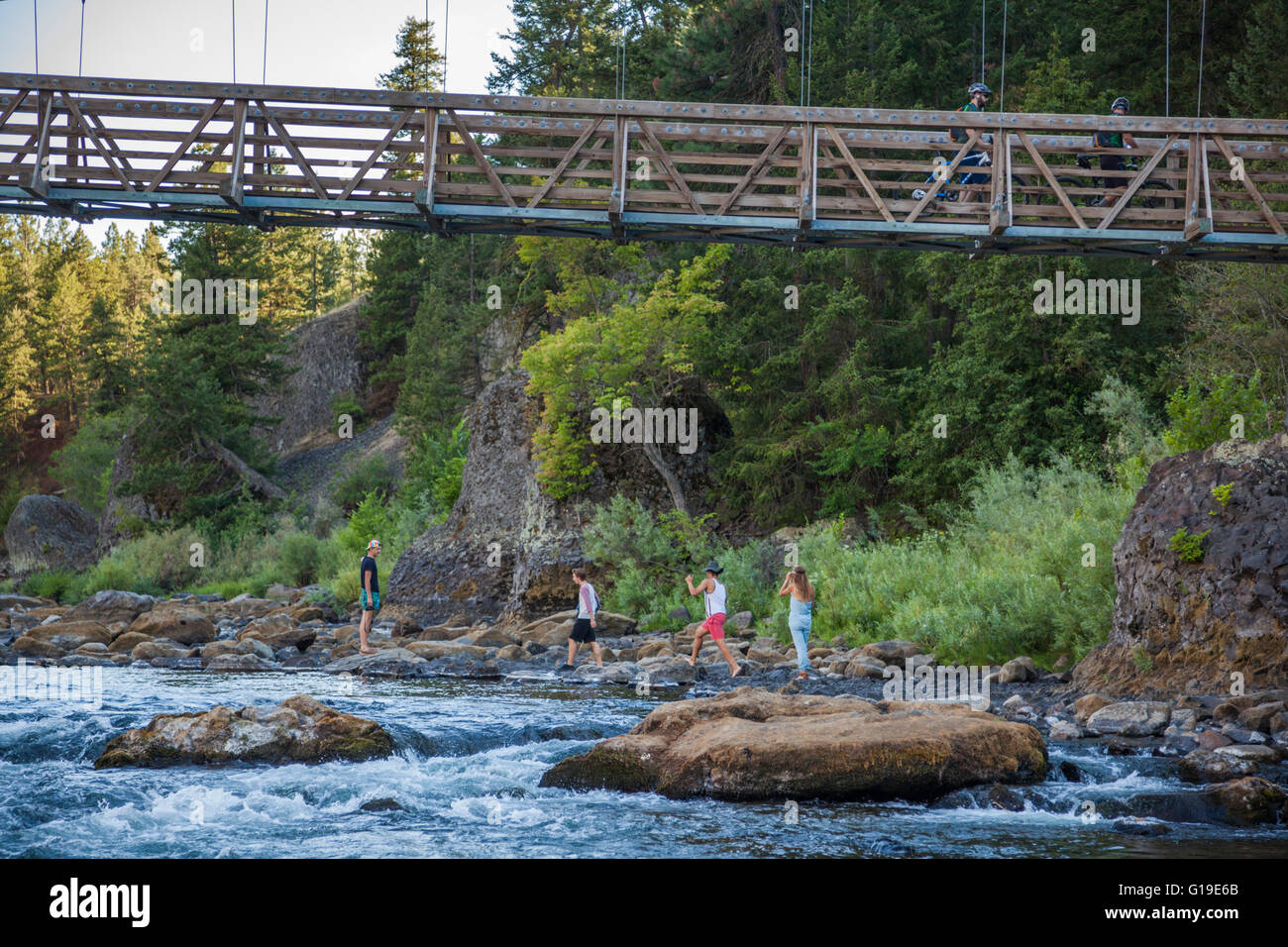 Les cyclistes traversent un pont tandis que les piétons explorer la rive de la rivière Spokane dans Riverside State Park, Washington. Banque D'Images