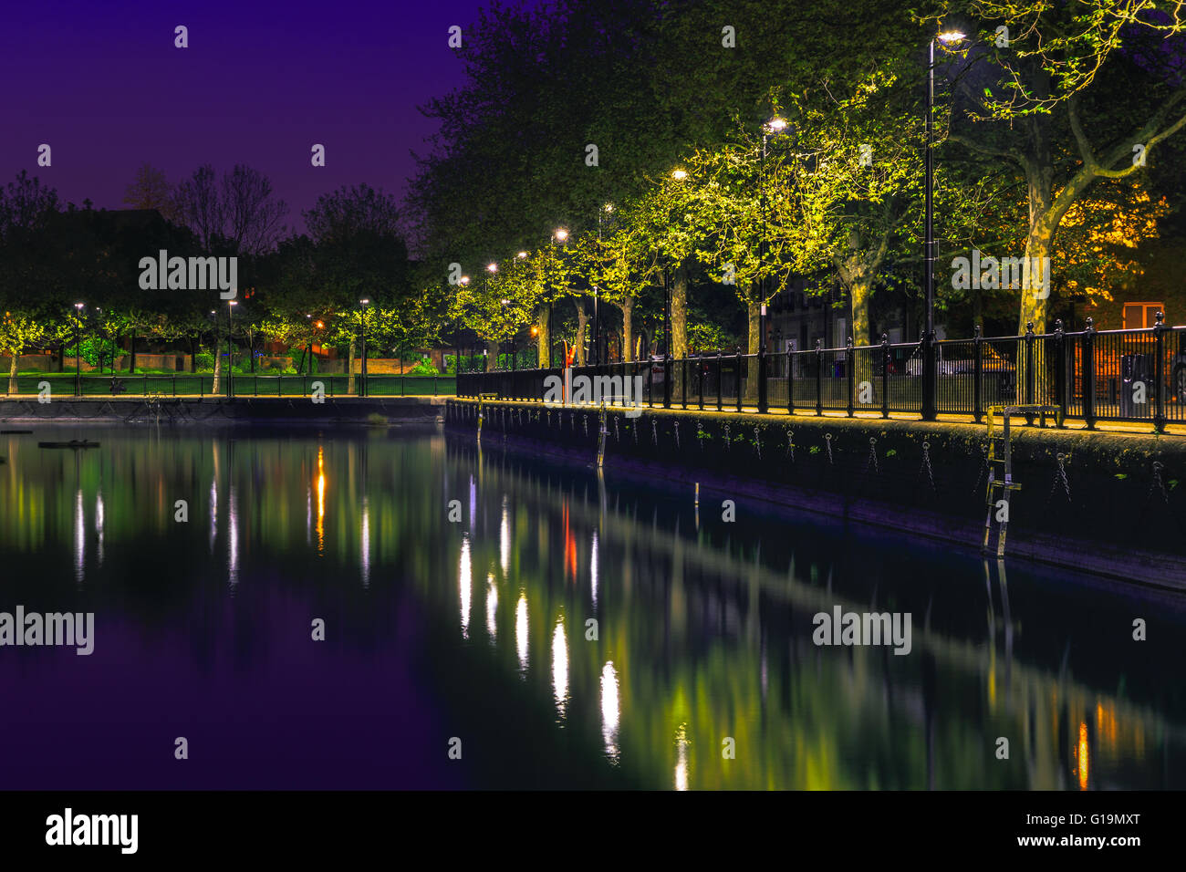 Rangée de lampadaires et leur réflexion à partir de l'eau de Surrey à Londres après le coucher du soleil Banque D'Images