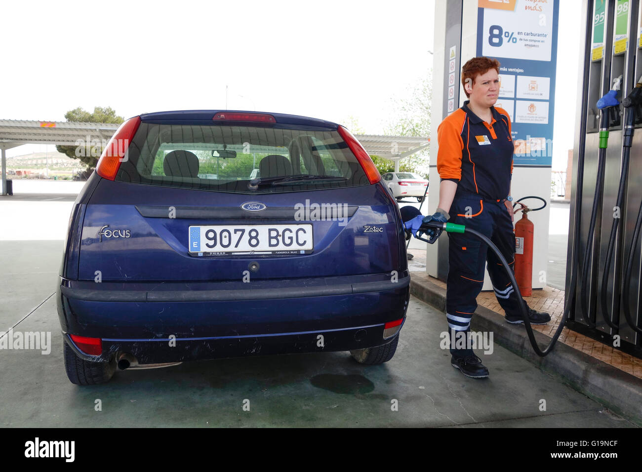 Femme pompiste, remplissage Ford Focus voiture à la station d'essence Repsol.Espagne. Banque D'Images