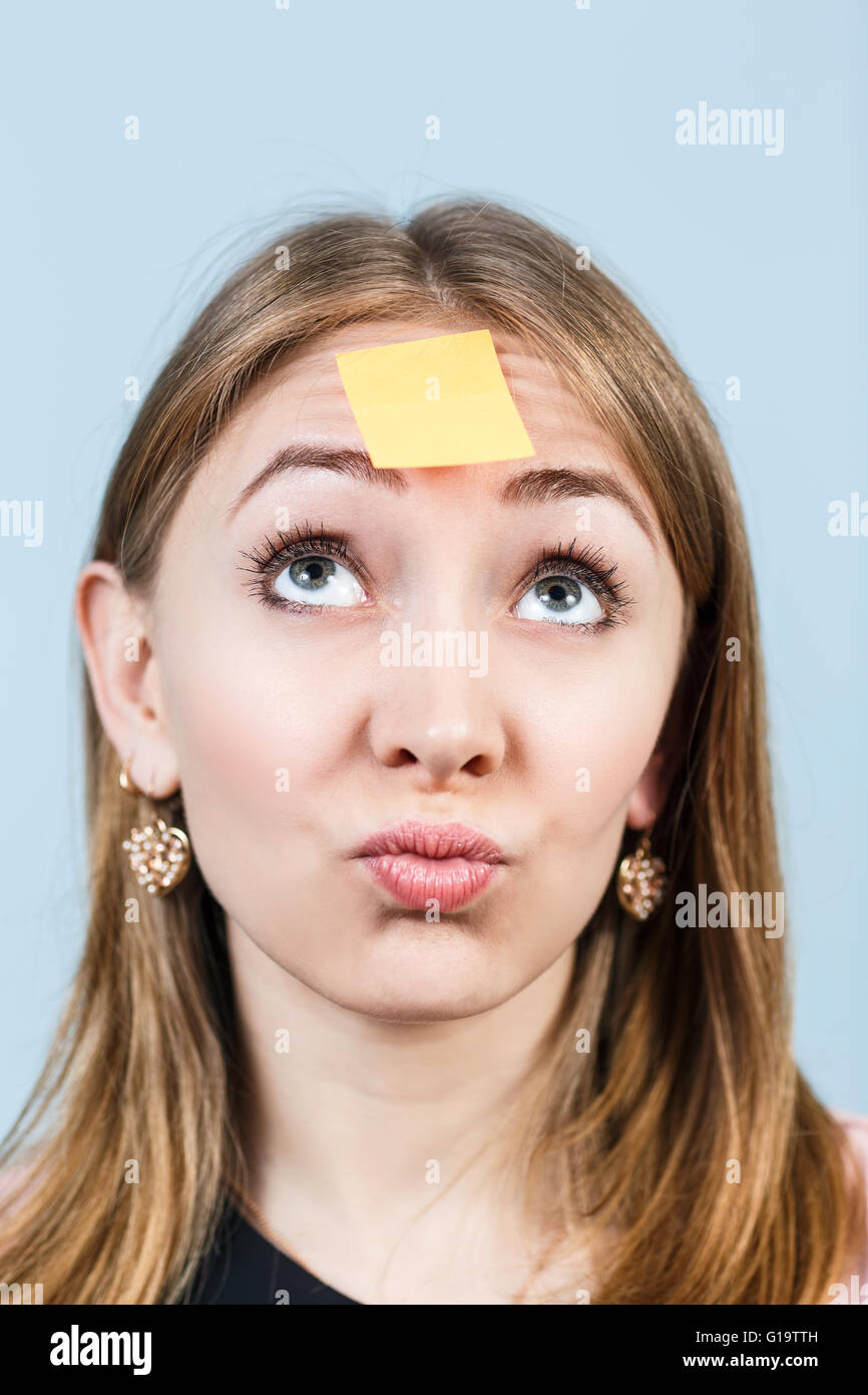 Un portrait d'une jeune femme confuse avec un post-it sur son front Banque D'Images