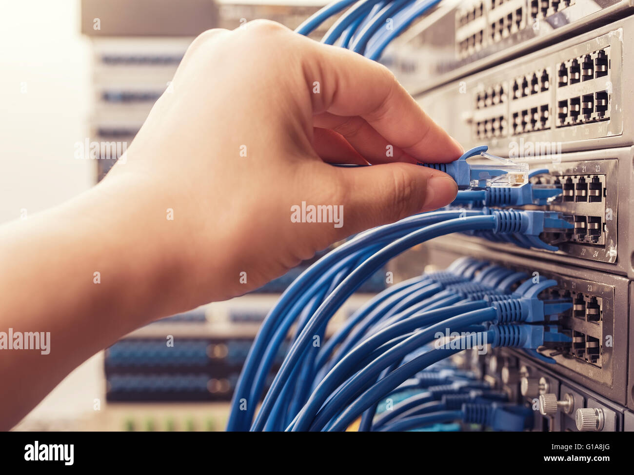 Homme travaillant dans network server room avec moyeu en fibre optique pour les communications numériques et internet Banque D'Images