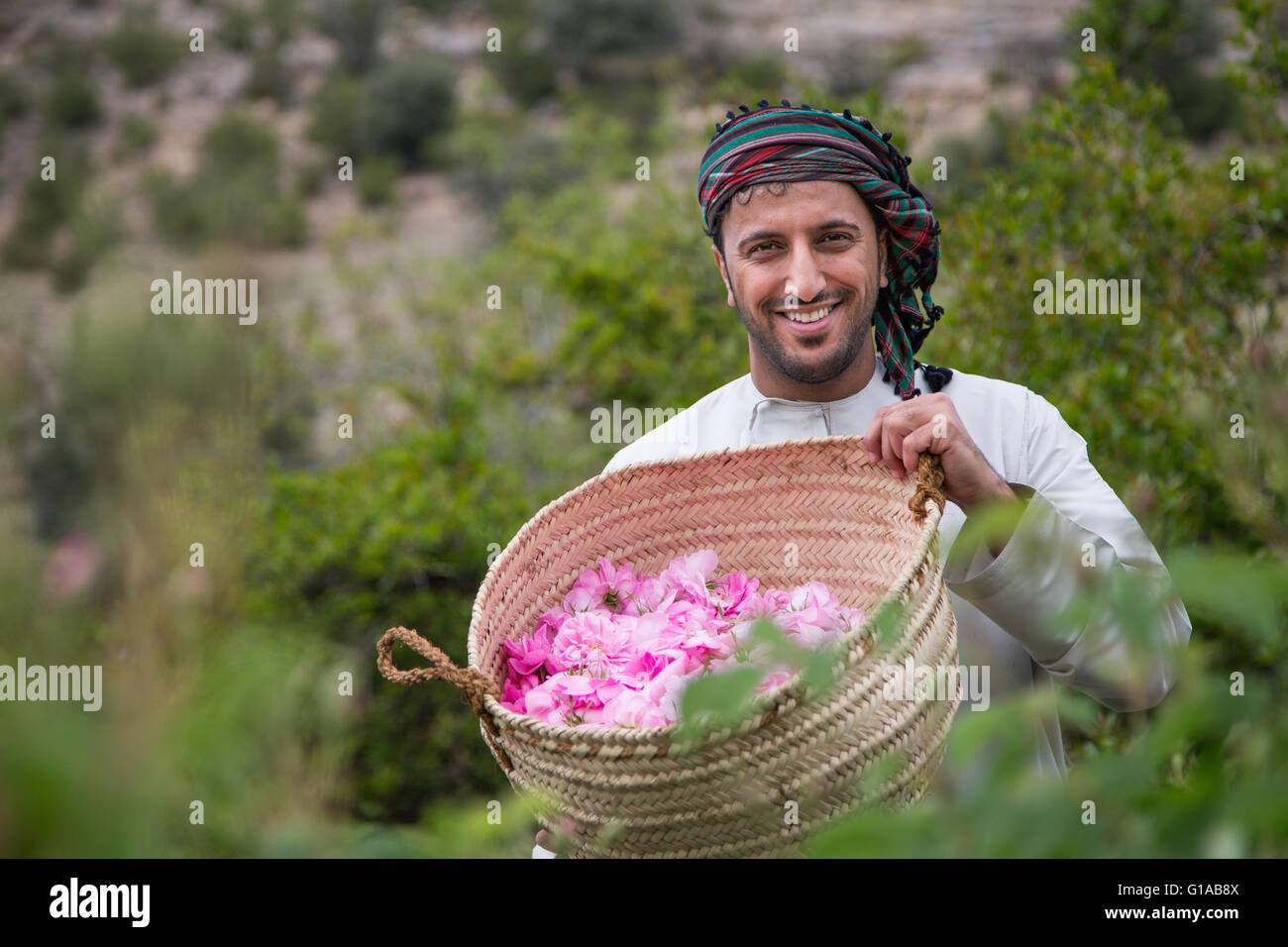 Les hommes en costume traditionnel omanais montrant outre de panier plein de pétales de rose Banque D'Images