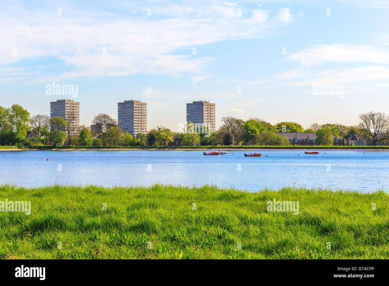 Vue de printemps de l'Ouest Stoke Newington réservoir, Hackney, Londres avec de l'herbe bien verte, ciel bleu et quelques bateaux flottants Banque D'Images