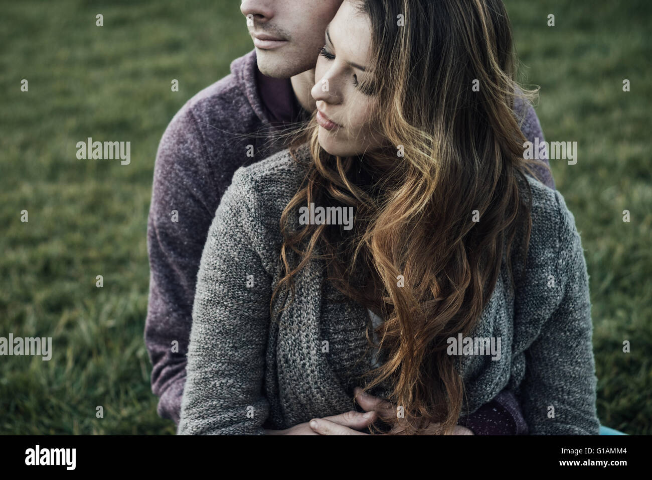 Couple romantique en plein air, ils sont assis sur l'herbe et des caresses, l'amour et les rapports concept Banque D'Images
