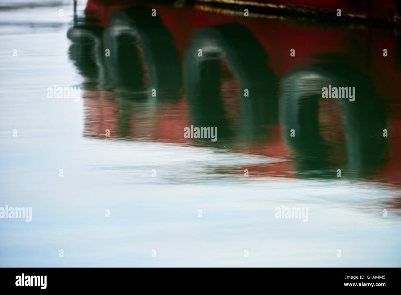 Bateau amarré avec de vieux pneus utilisés comme garde-boue créer des réflexions à Cobh Harbour Banque D'Images