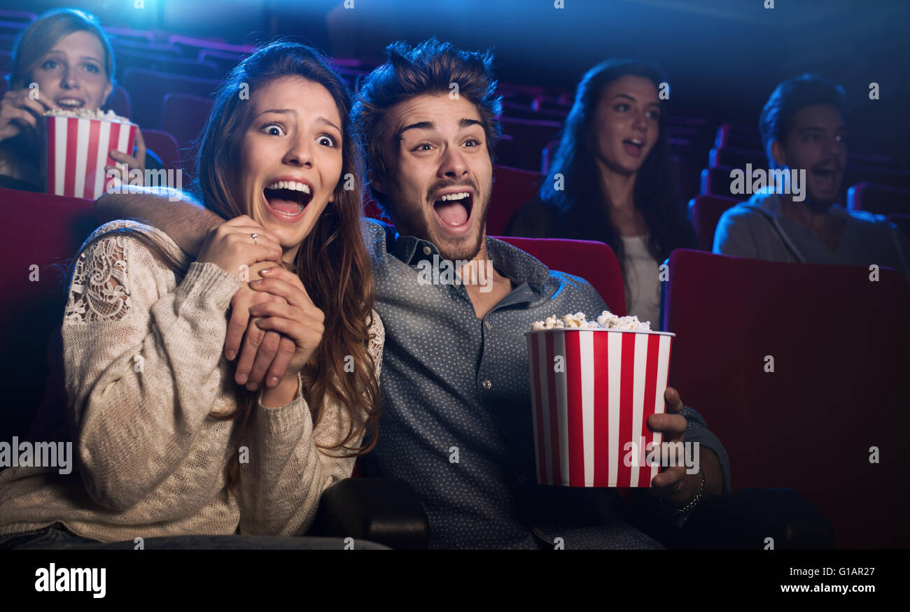 Jeune couple peur au cinéma en regardant un film d'horreur et les cris, elle tient la main de son petit ami Banque D'Images