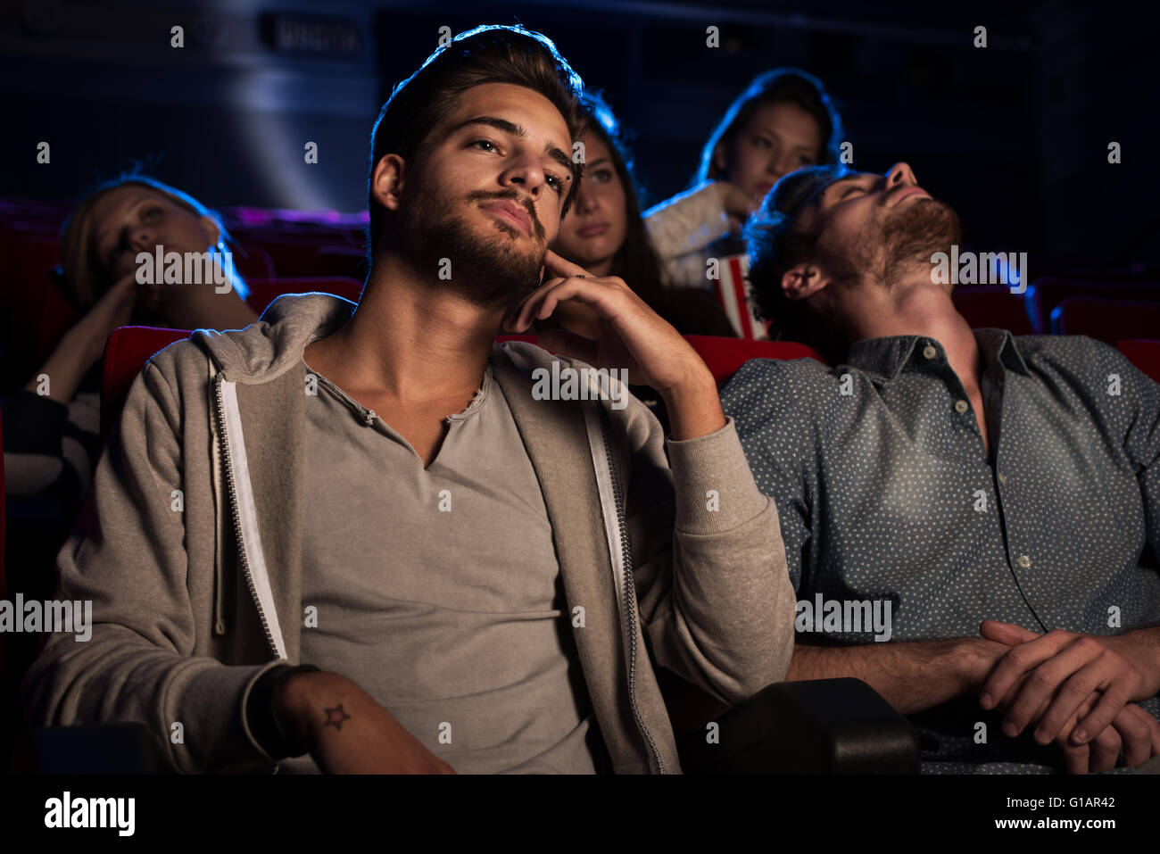 Les jeunes gens qui regardent un film ennuyeux au cinéma, un gars est en train de dormir Banque D'Images