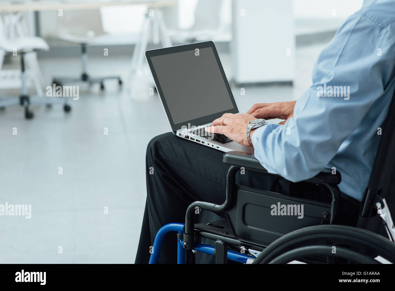 Homme d'entreprise en fauteuil roulant à l'aide d'un ordinateur portable et la mise en réseau, personne méconnaissable Banque D'Images