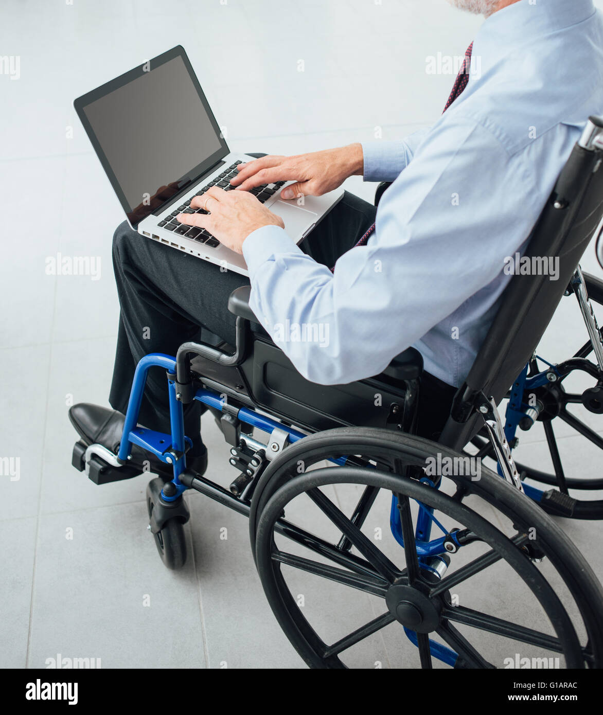 Homme d'entreprise en fauteuil roulant à l'aide d'un ordinateur portable et la mise en réseau, personne méconnaissable Banque D'Images