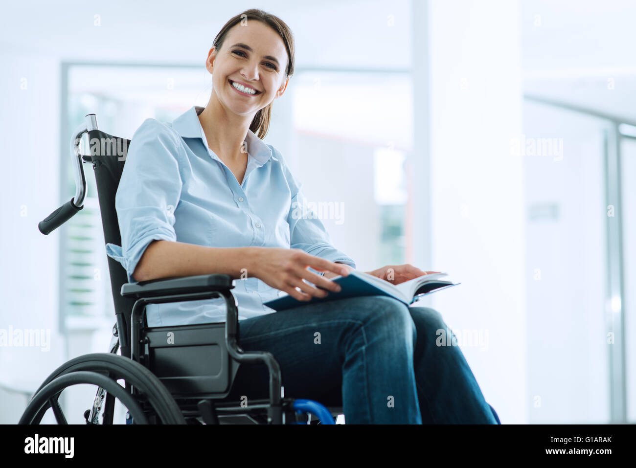 Smiling young woman in wheelchair looking at camera Banque D'Images