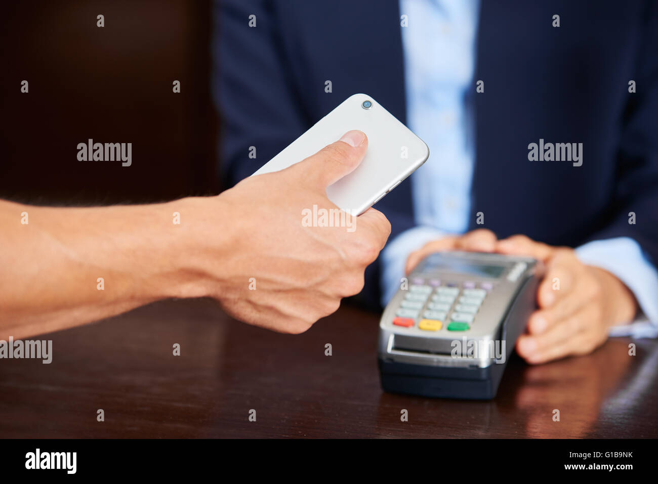 Guest payer avec son projet de smartphone à la réception de l'hôtel Banque D'Images