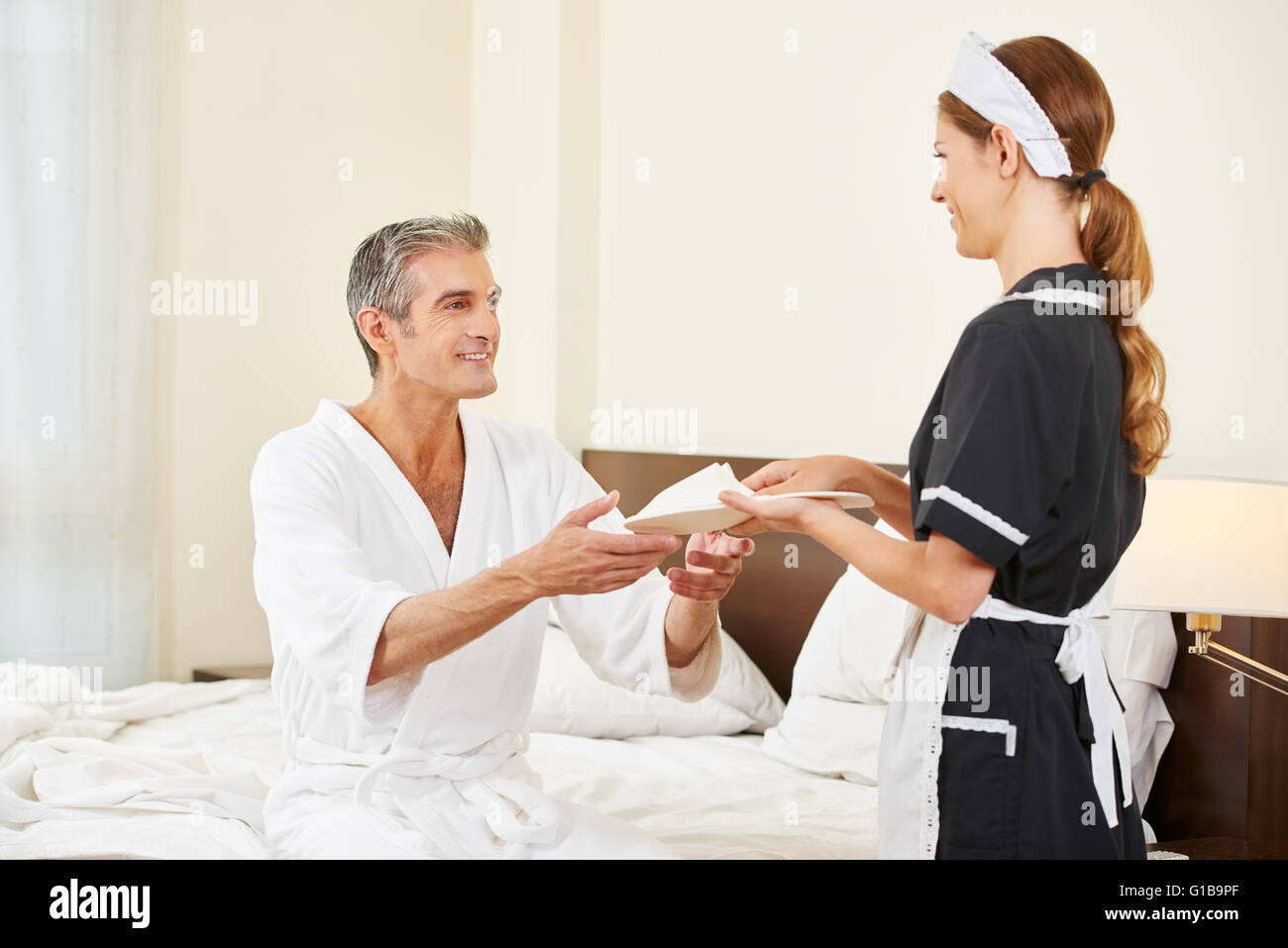 Hotel maid portant des chaussons pour invité dans une chambre d'hôtel Banque D'Images