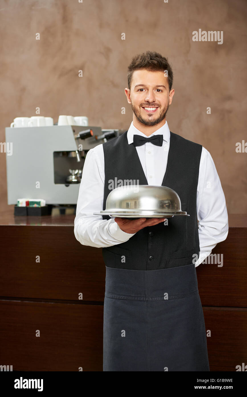 Garçon en uniforme avec cloche alimentaire dans un restaurant de l'hôtel Banque D'Images