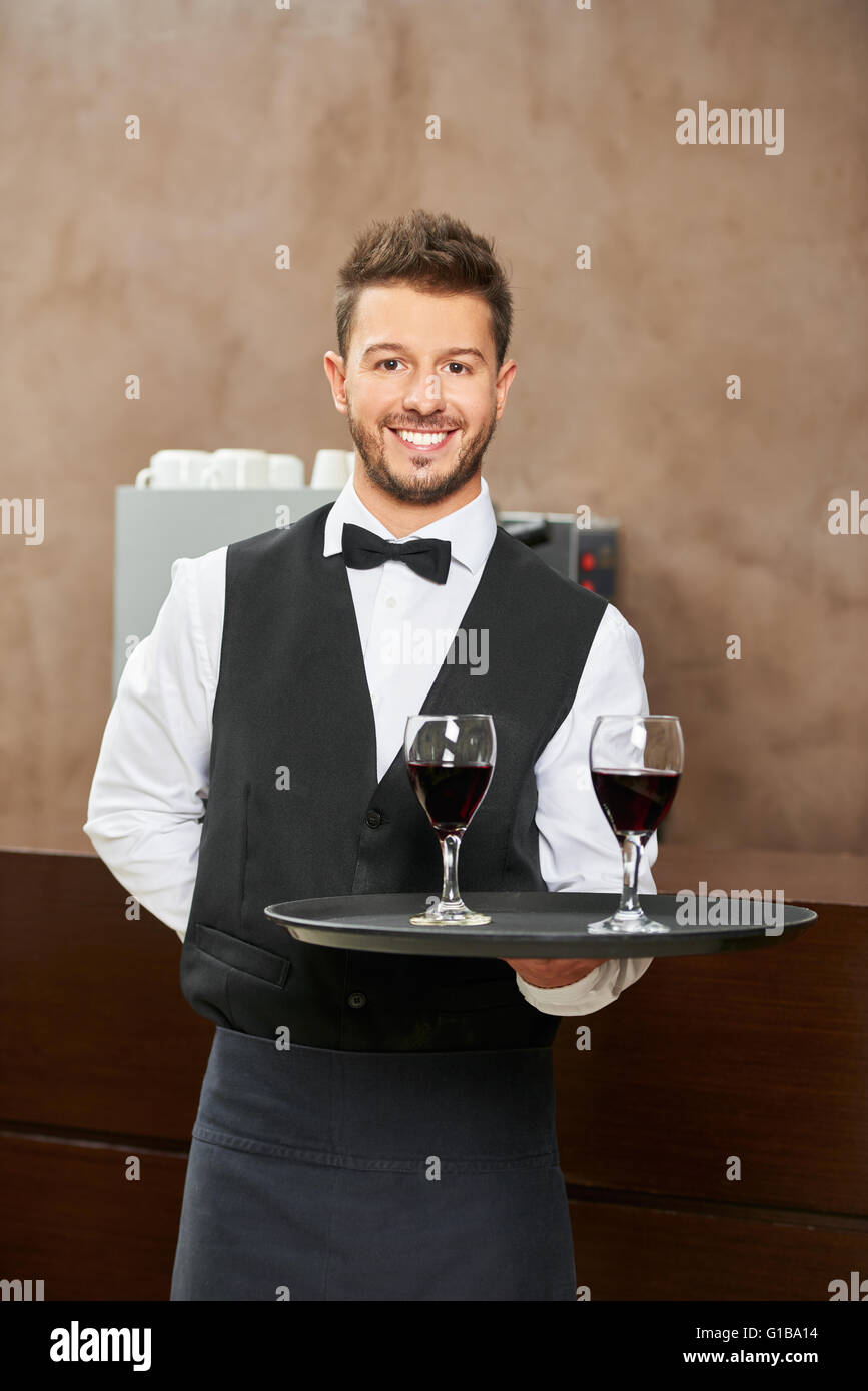 Garçon en uniforme qui servent le vin rouge dans un restaurant de l'hôtel Banque D'Images