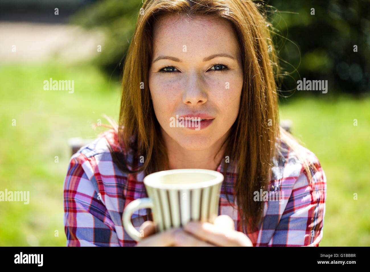 Portrait d'une femme à l'extérieur d'un café ou thé potable regardant la caméra détendue et réfléchie Banque D'Images