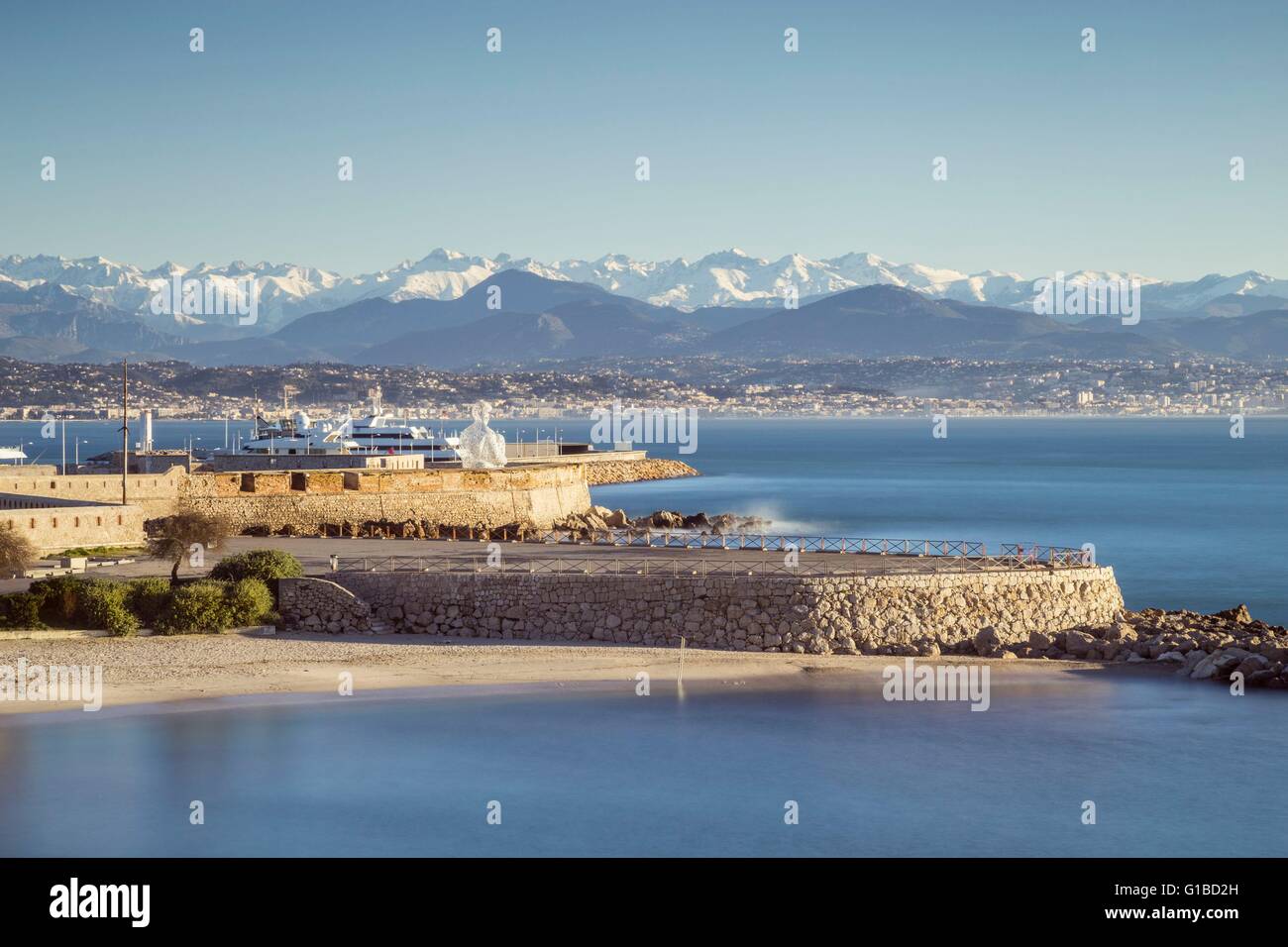 France, Alpes Maritimes, plage de la Gravette, la sculpture monumentale nomade d'Antibes du Catalan Jaume Plensa sur les remparts du port Vauban et à l'arrière terrain neigeux de l'Alpes du Sud Banque D'Images