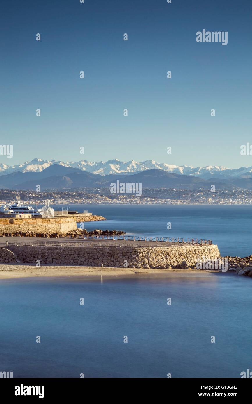 France, Alpes Maritimes, plage de la Gravette, la sculpture monumentale nomade d'Antibes du Catalan Jaume Plensa sur les remparts du port Vauban et à l'arrière terrain neigeux de l'Alpes du Sud Banque D'Images