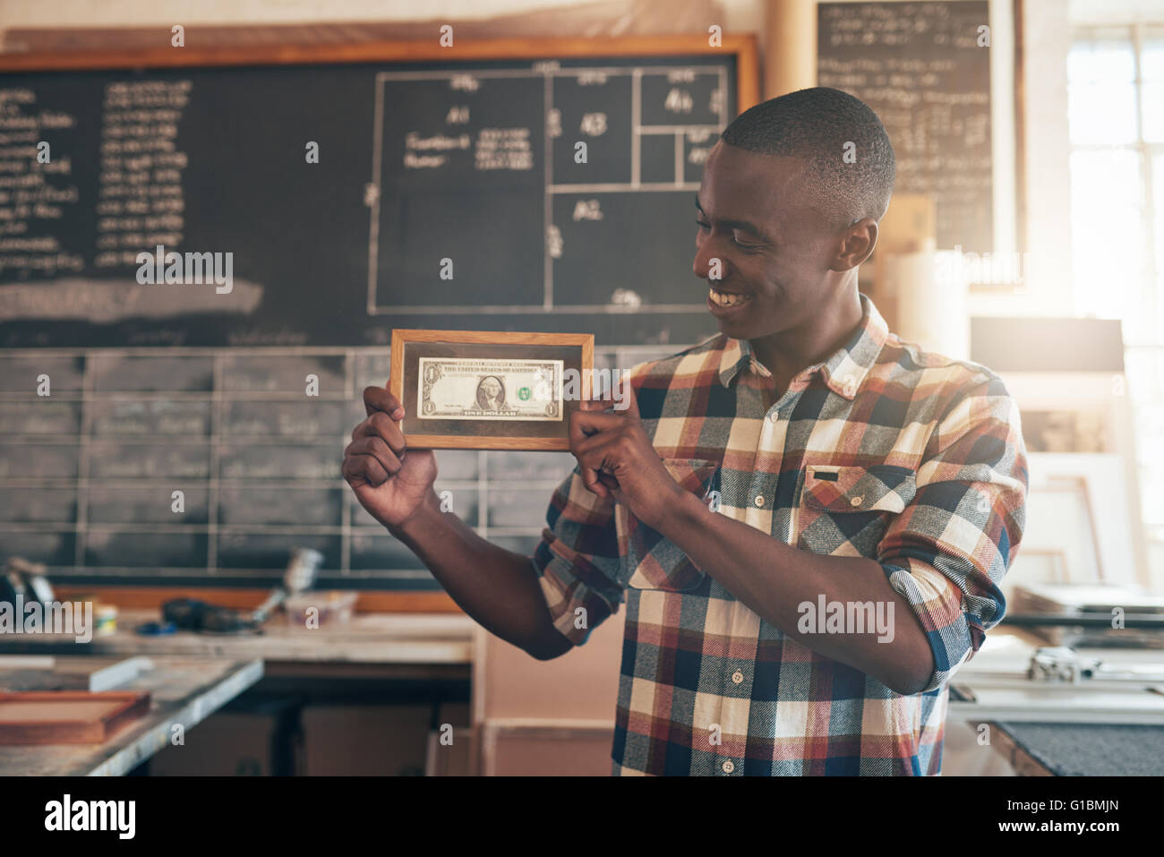Jeune africain fier propriétaire de l'entreprise montrant le premier dollar bill son entreprise jamais gagné, montrant la valeur de l'enquête Banque D'Images