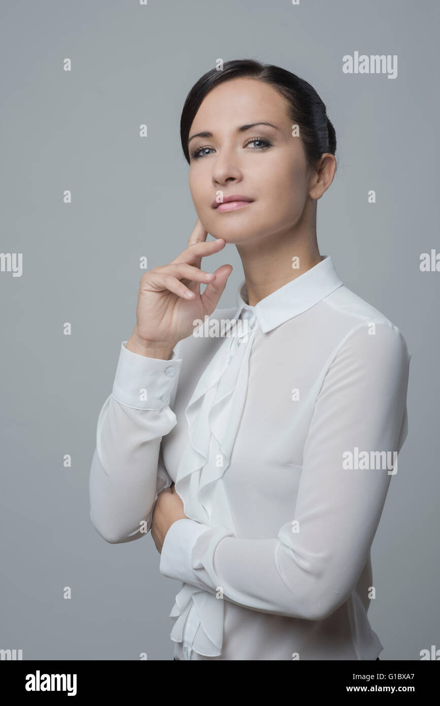 Attractive Woman in white shirt with hand on chin, smiling at camera. Banque D'Images