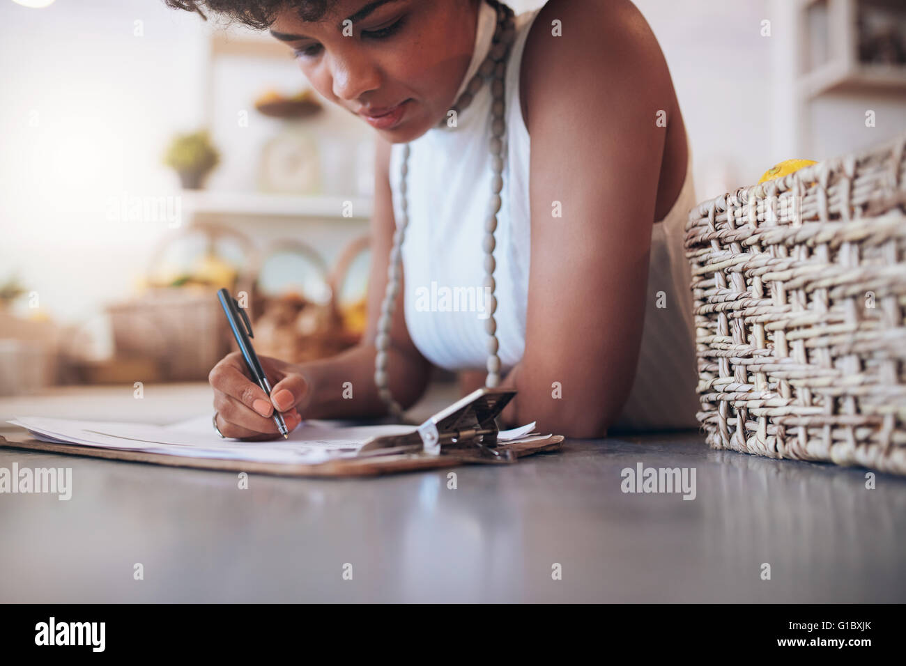Portrait de jeune femme africaine travaillant dans un bar à jus. Femme debout derrière le comptoir, et la rédaction de notes. Le calcul d'un Banque D'Images