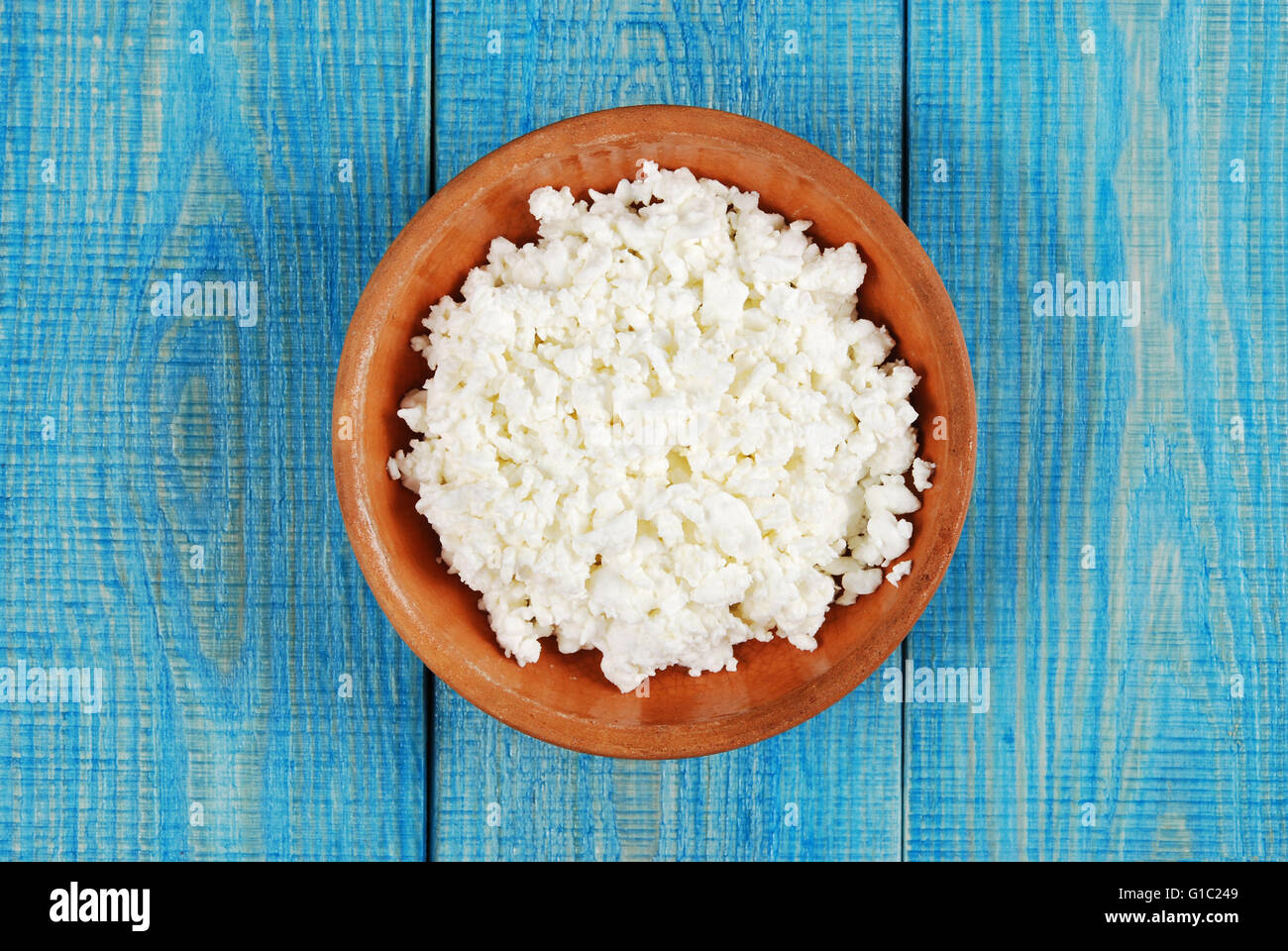 Le fromage blanc dans un petit bol brun sur un fond de bois bleu Banque D'Images