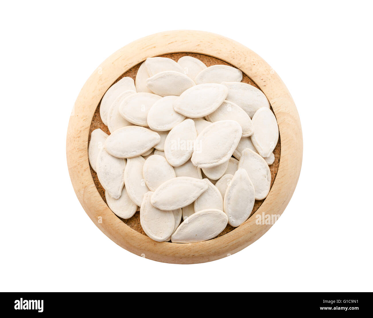 Graines de potiron dans un plat en bois isolé sur fond blanc, sauver chemin de détourage. Banque D'Images