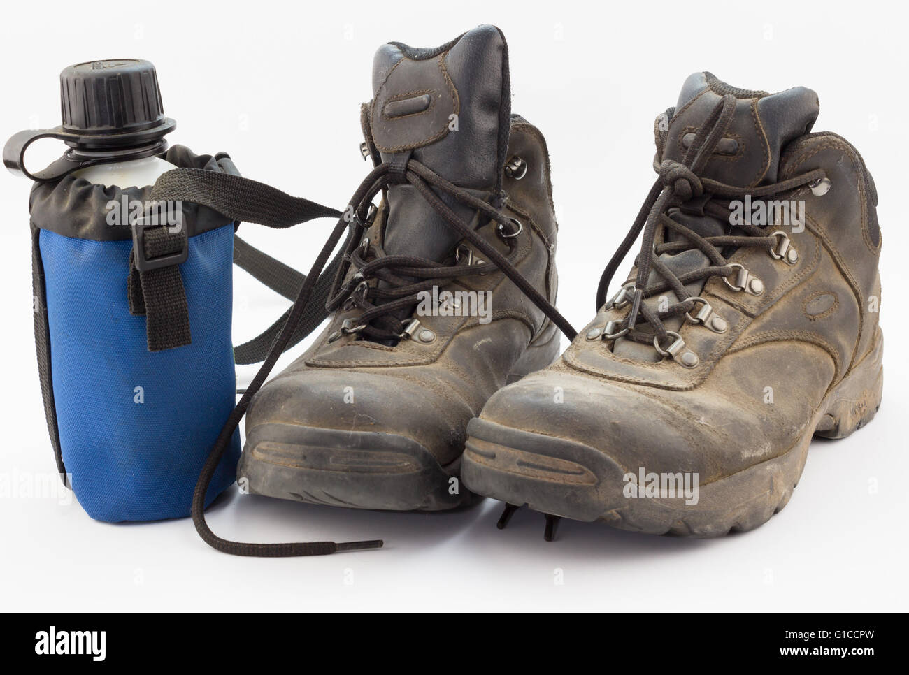 Close up of dusty porté des bottes de randonnée avec de l'eau bouteille sur white Banque D'Images
