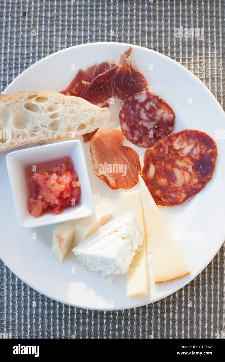 Une assiette pleine de viande mixte composé de jambon, chorizo et salami, fromage, pain et tomate. Banque D'Images