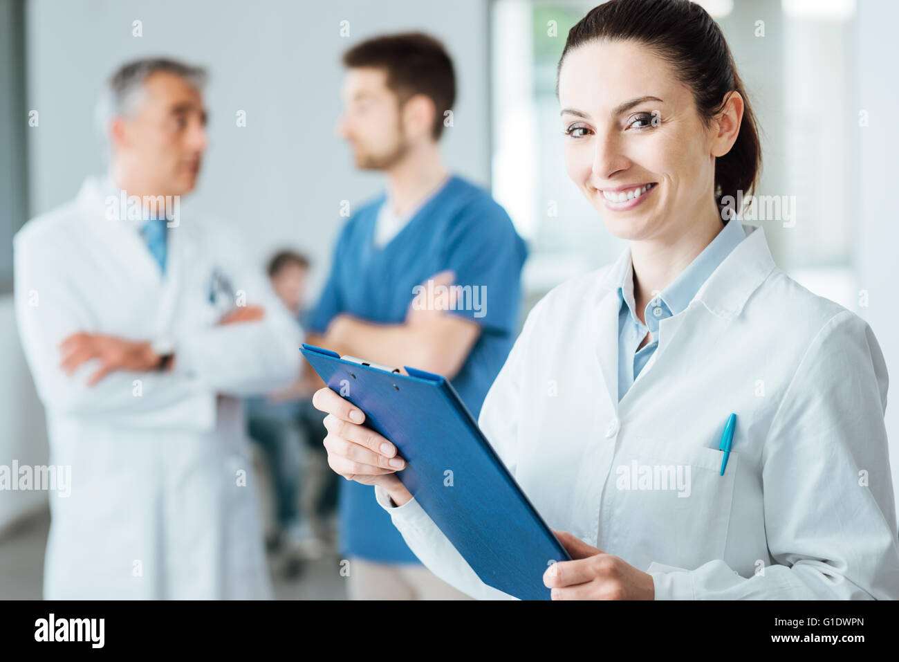Professional female doctor smiling at camera et posant, le personnel médical travaillant sur background, selective focus Banque D'Images Professional female doctor smiling at camera et posant, le personnel médical travaillant sur background, selective focus Banque D'Images