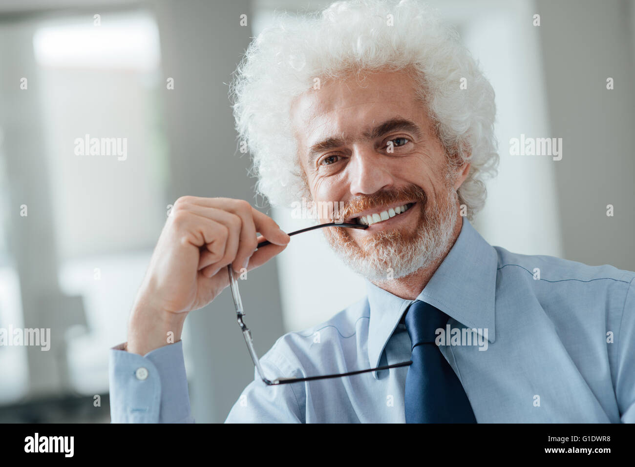 Cheerful businessman portrait, il est holding glasses and looking at camera Banque D'Images