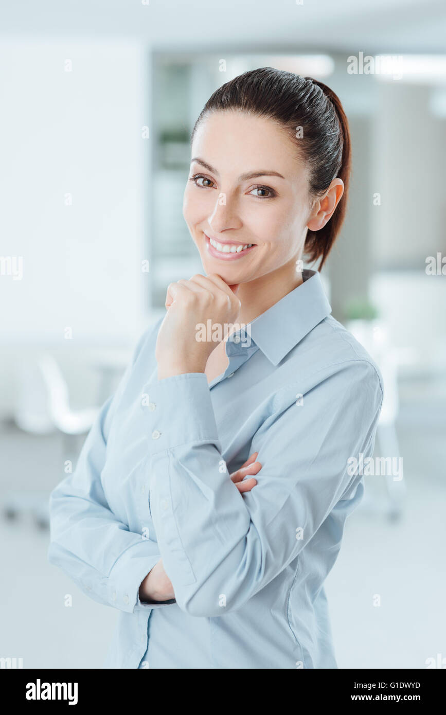 Woman posing with hand on chin and smiling at camera Banque D'Images